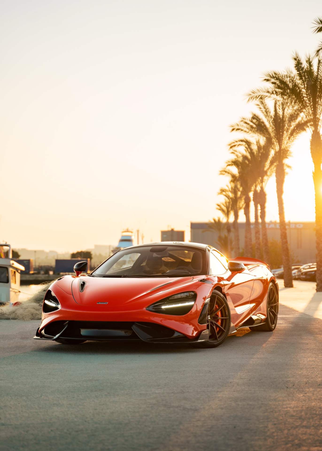 McLaren naranja al atardecer entre palmeras