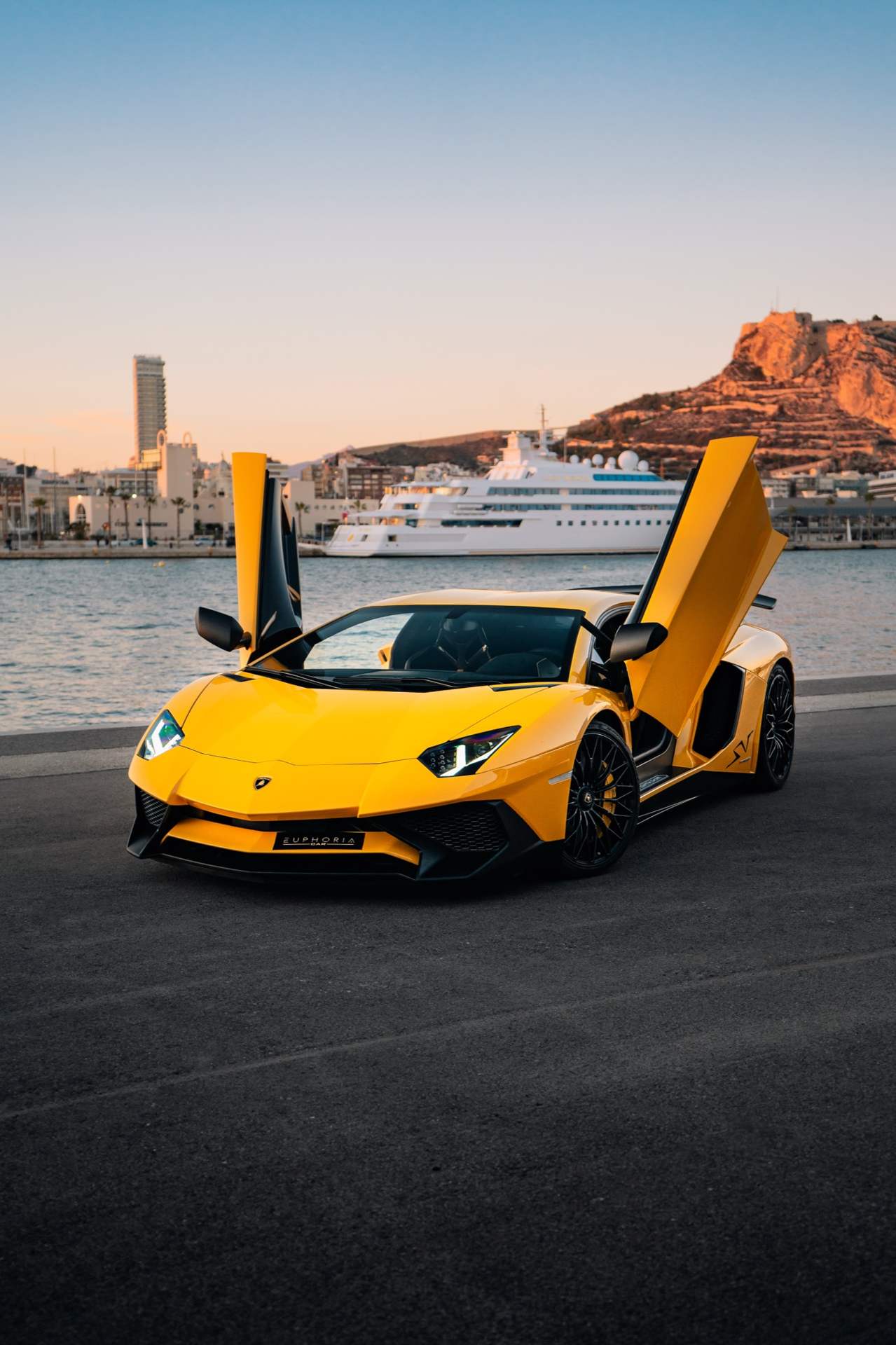 Lamborghini amarillo con las puertas abiertas junto al mar