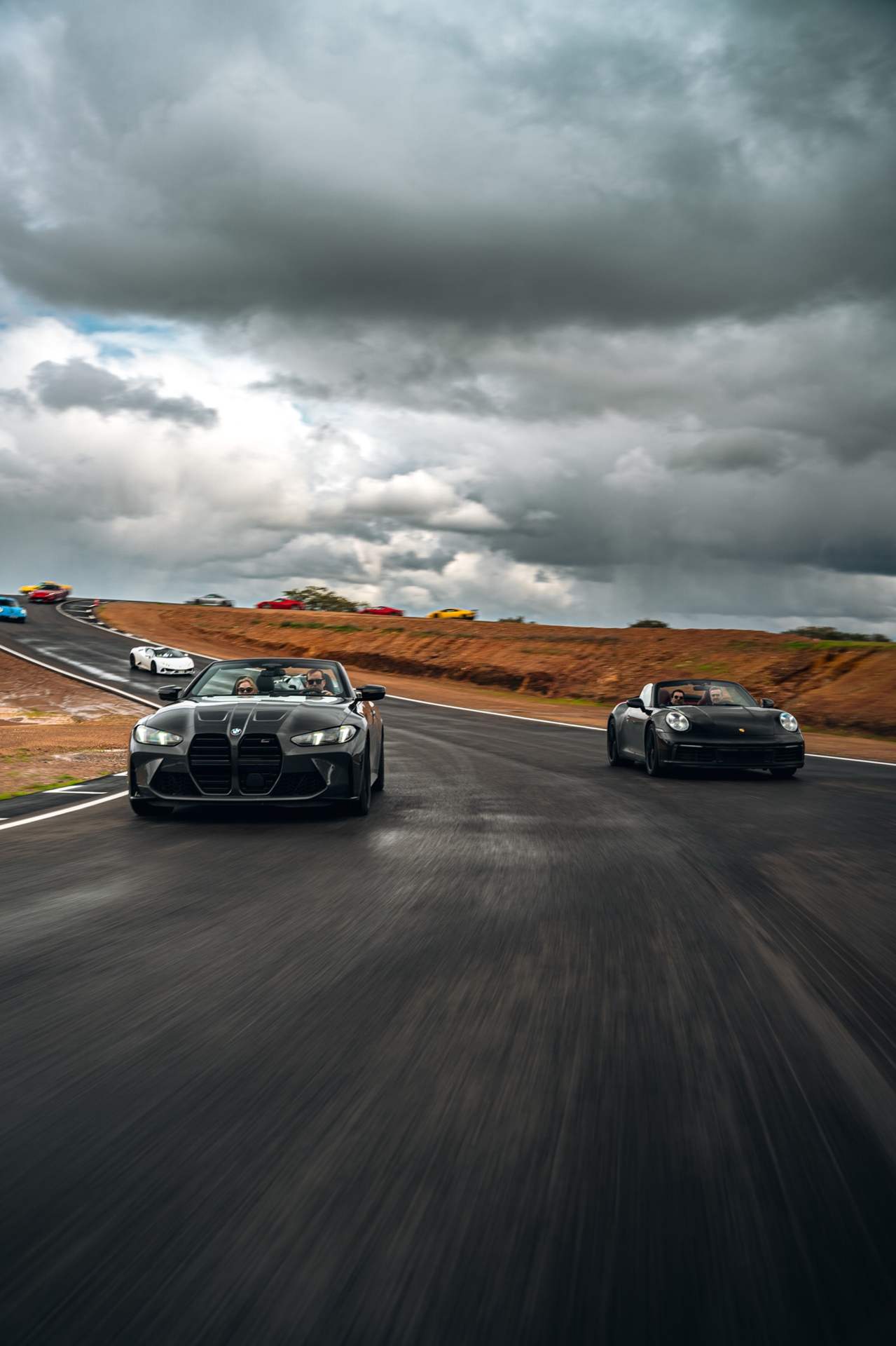 Coches rodando en un circuito bajo un cielo de tormenta